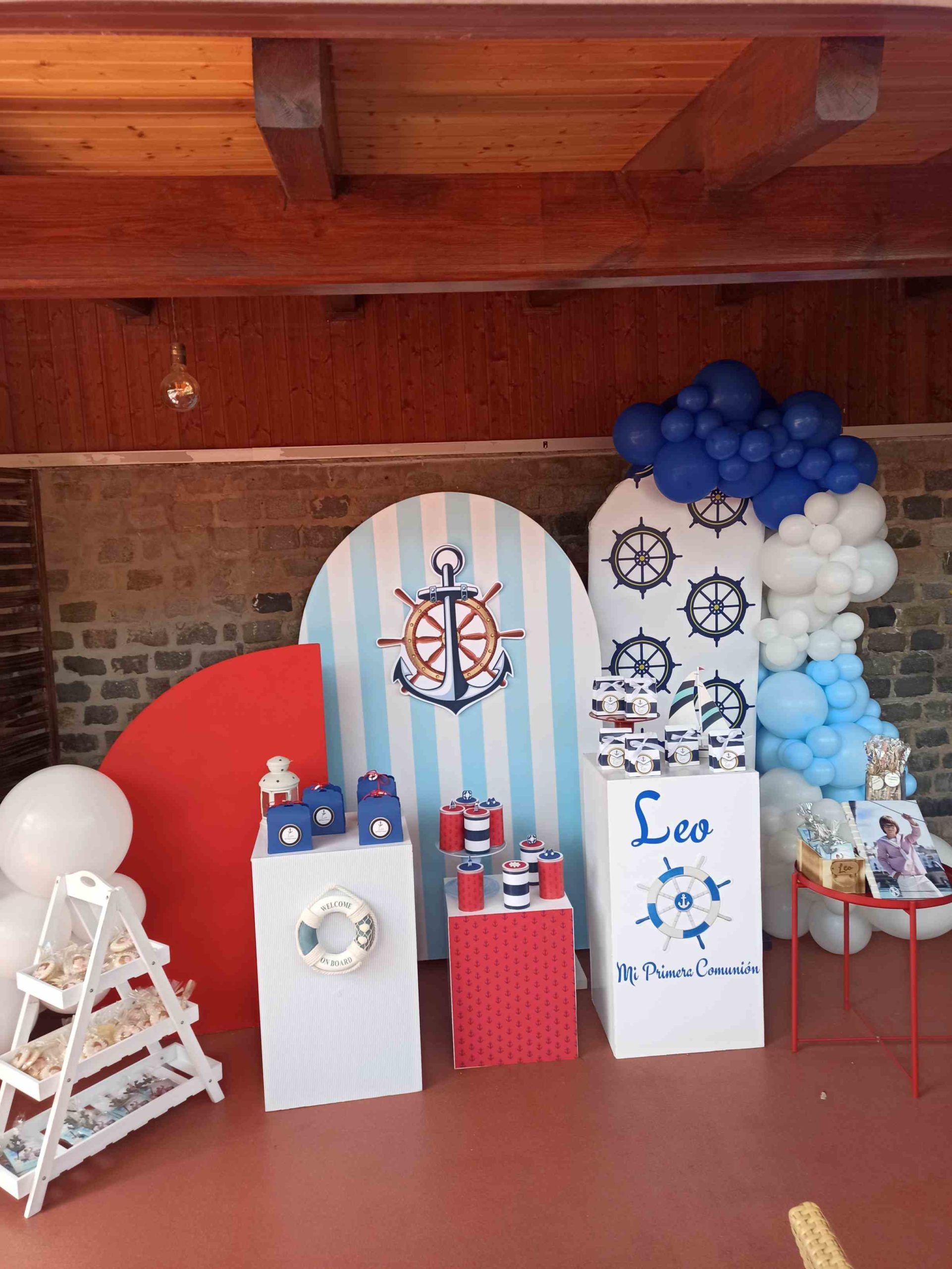 Decoración con paneles traseros con motivos marinos, como anclas y timones y con el nombre del agasajado y con cajitas de dulces a juego con la temática y personalizados con el motivo del evento