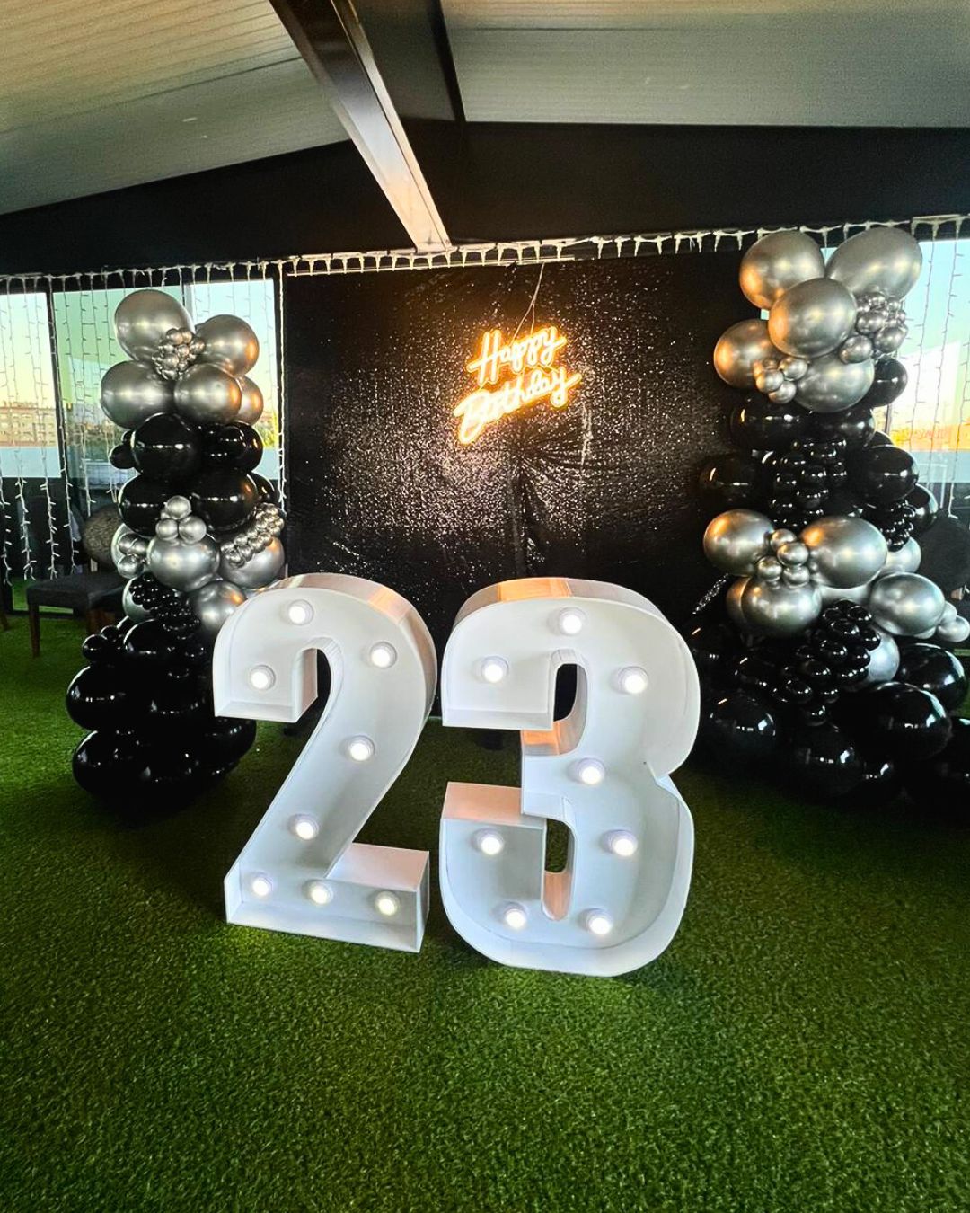 Photocall Cumpleaños 23 años letras blancas con backing negro, guirnaldas de globos dorados, plata y negros