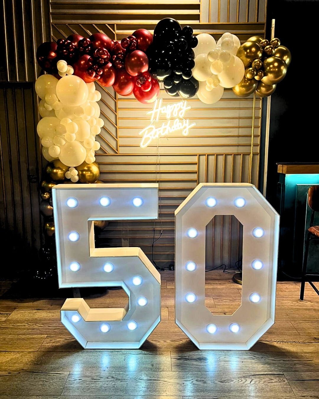 Photocall Cumpleaños 50 años negros, blancos y rojos con backing blanco, guirnaldas de globos dorados, plata y negros