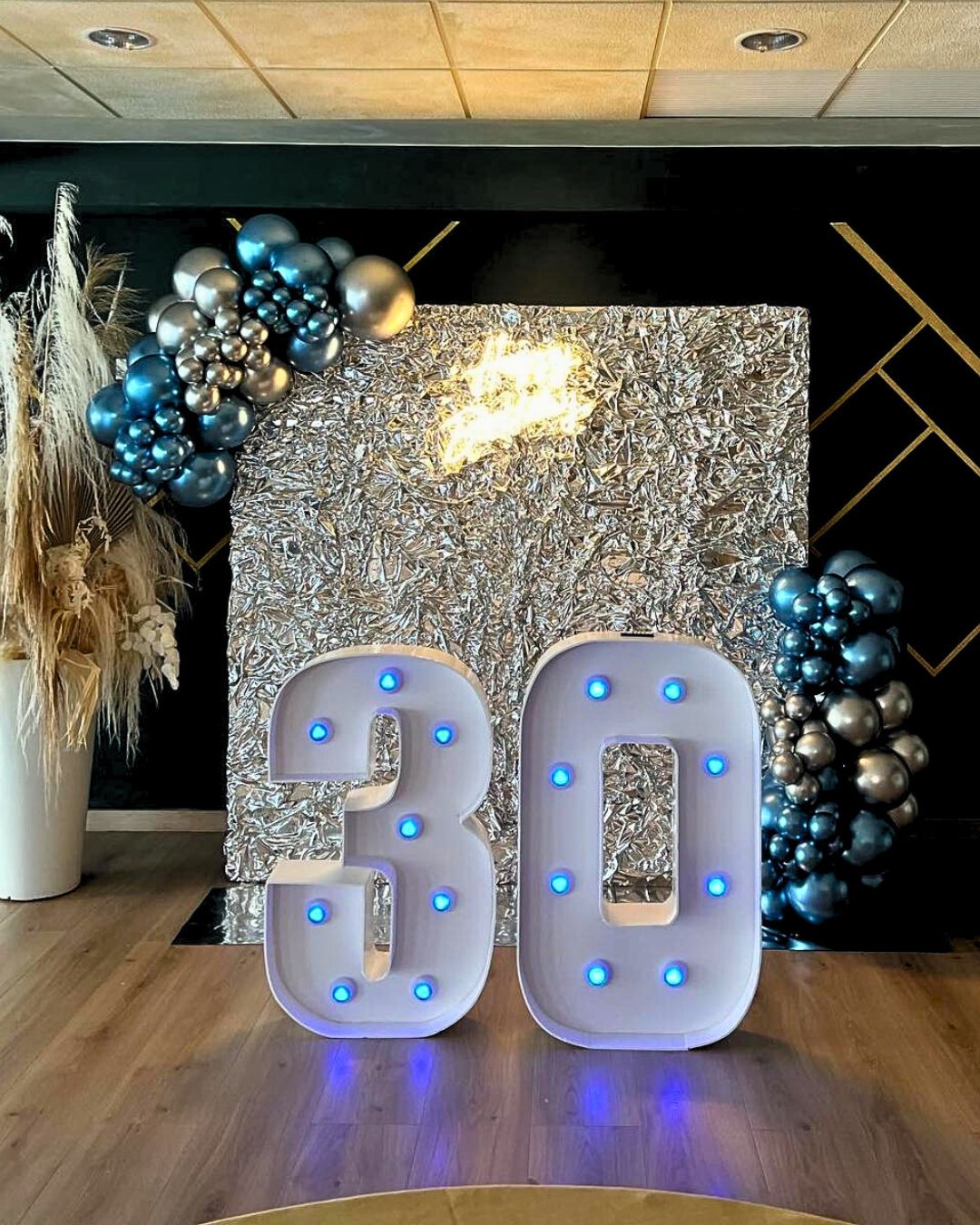 Photocall Cumpleaños 50 años negros, blancos y rojos con backing blanco, guirnaldas de globos azules y plata